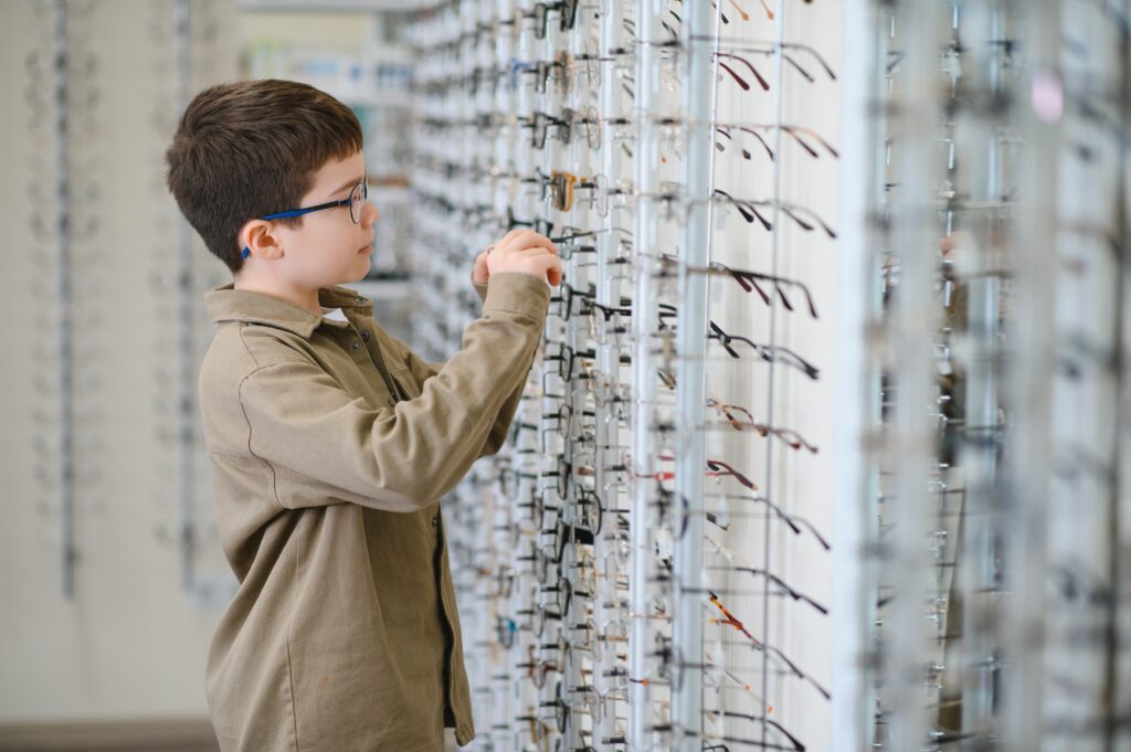 Boy trying on glasses in optometrists office.